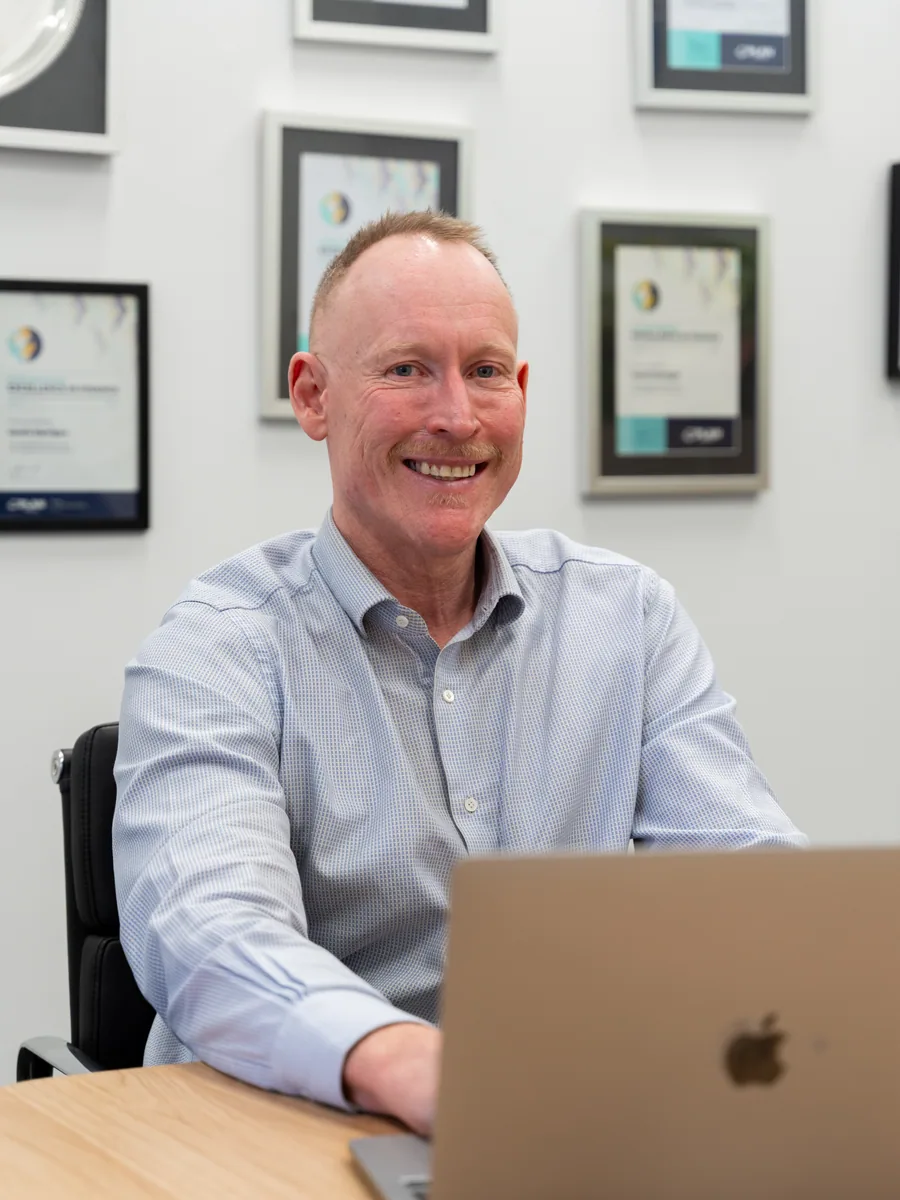 Gavin Harrigan at his desk at the Quantum Finance office in West Leederville, industry awards on the wall behind him