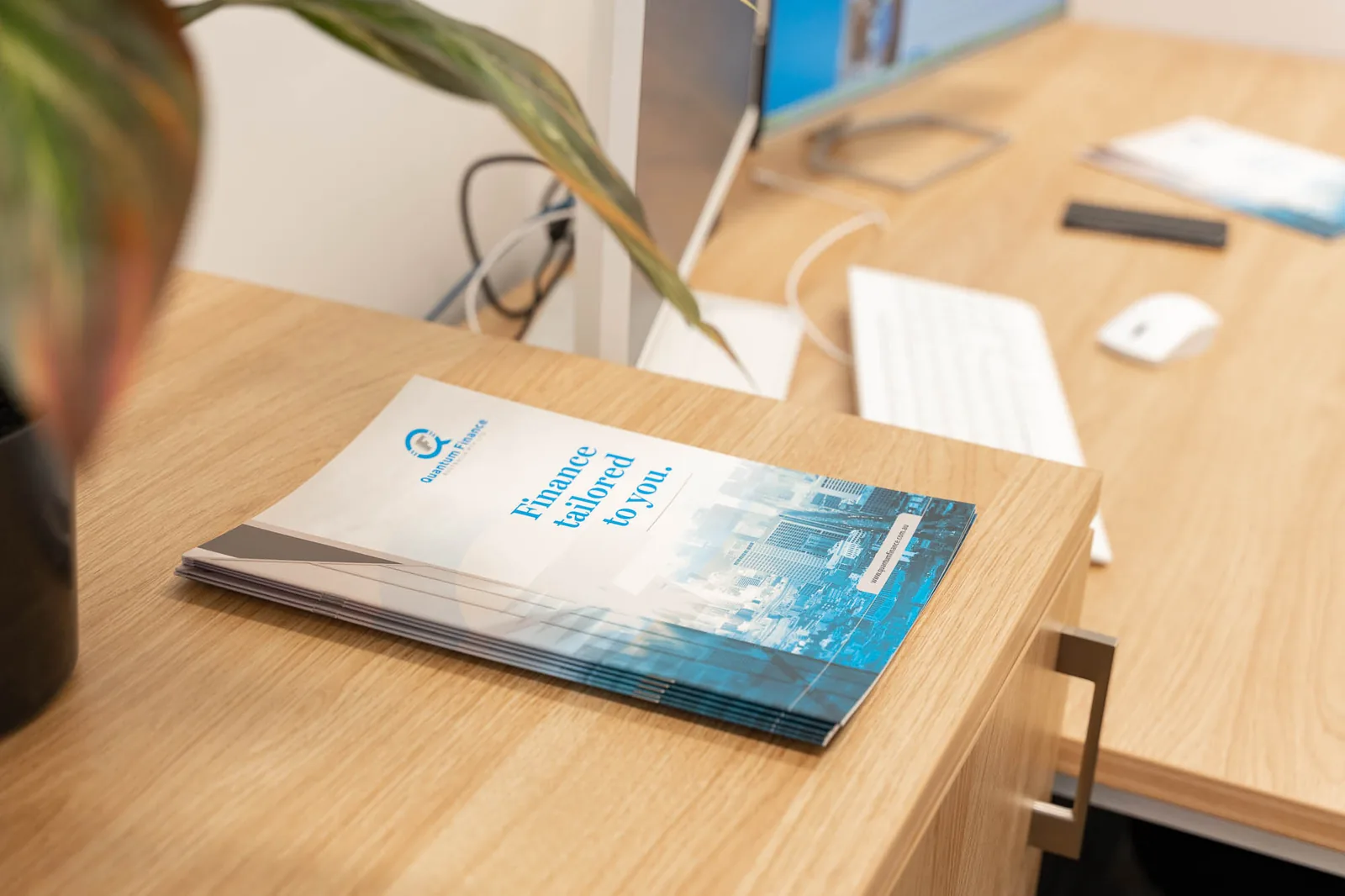 A Quantum Finance brochure and business card laid out on a desk in the West Leederville office
