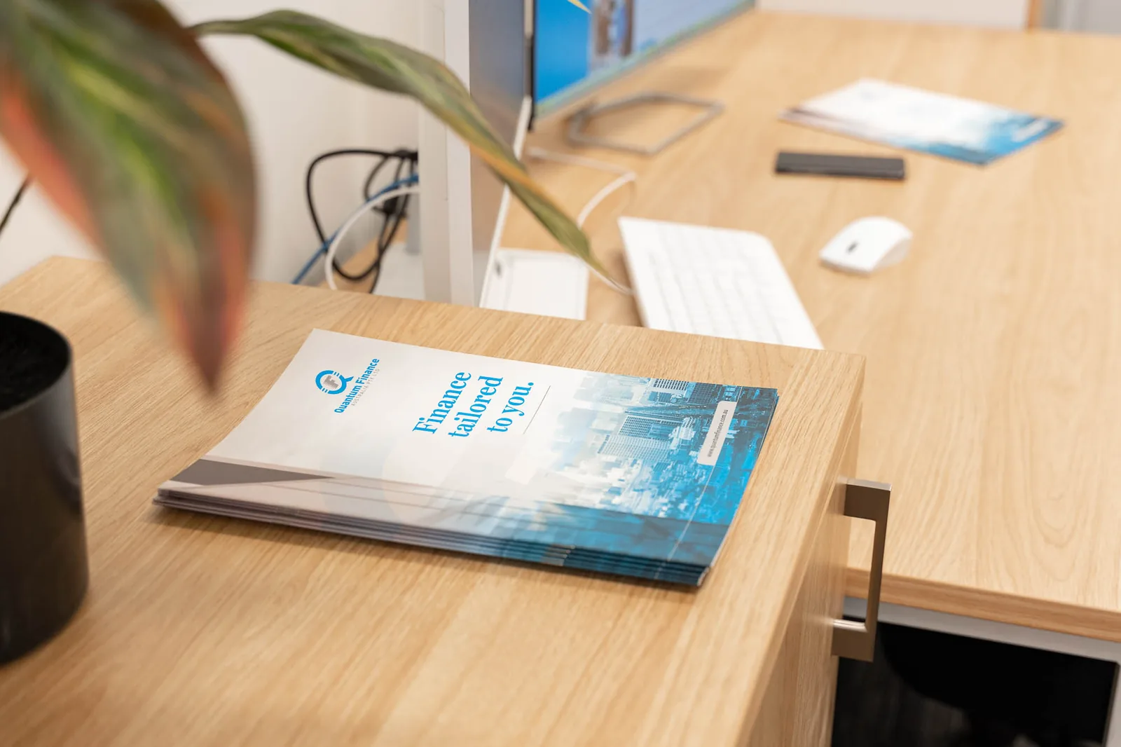 Quantum Finance brochures on a desk beside a planter