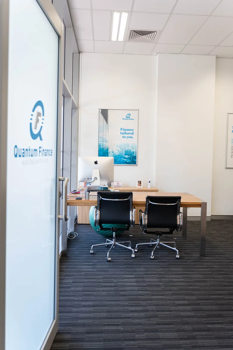 A consulting room at the Quantum Finance office seen through a branded glass door