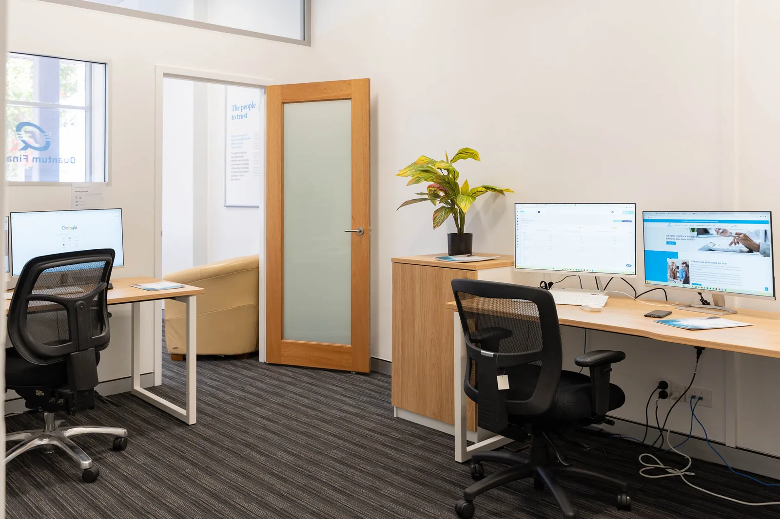 A desk in the Quantum Finance office with a monitor and a planter beside it