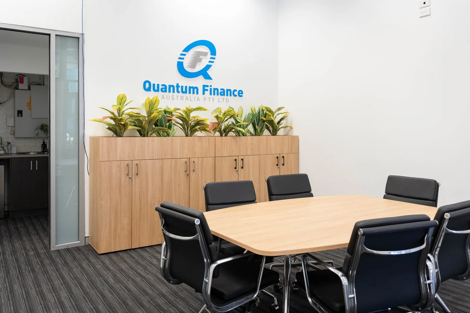 A meeting room at Quantum Finance with the branded wall behind the table