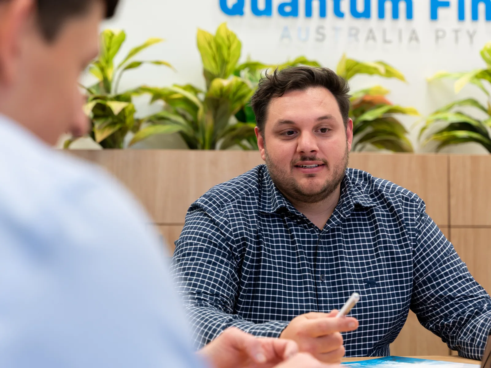 A Quantum Finance broker taking a buyer through a purchase at the meeting table