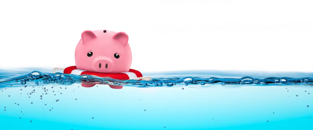 A piggly bank floating just staying above water.