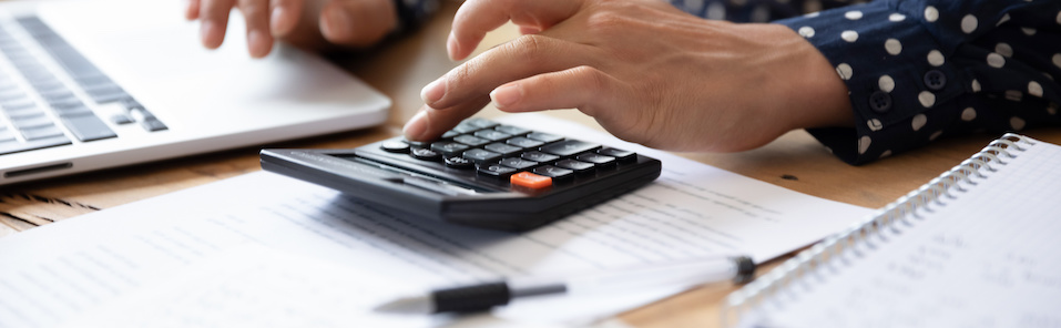 Woman using a calculator to work out the feasibility of refinancing.